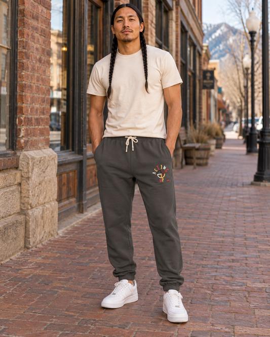 AI-generated lifestyle mockup of pepper grey embroidered Acting Up sweatpants on a braided male model in Montana.