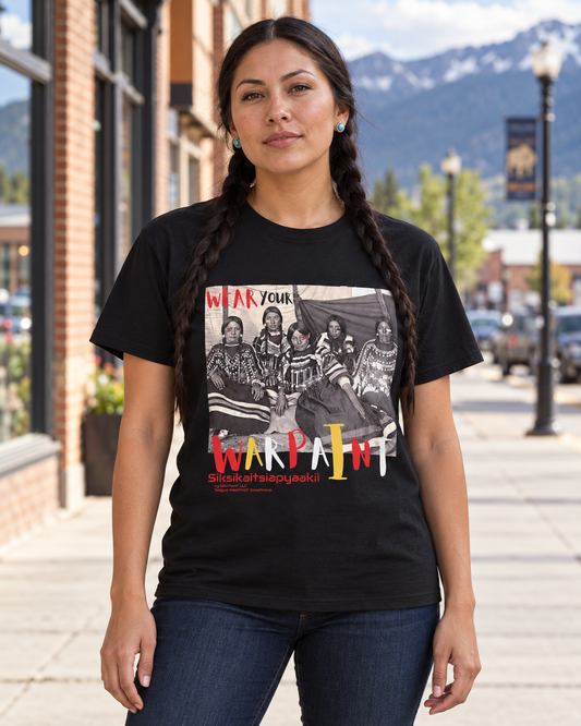 AI-generated lifestyle mockup of the black Siksikaitsiapyaakii Blackfoot Woman tee on a braided female model in Montana.