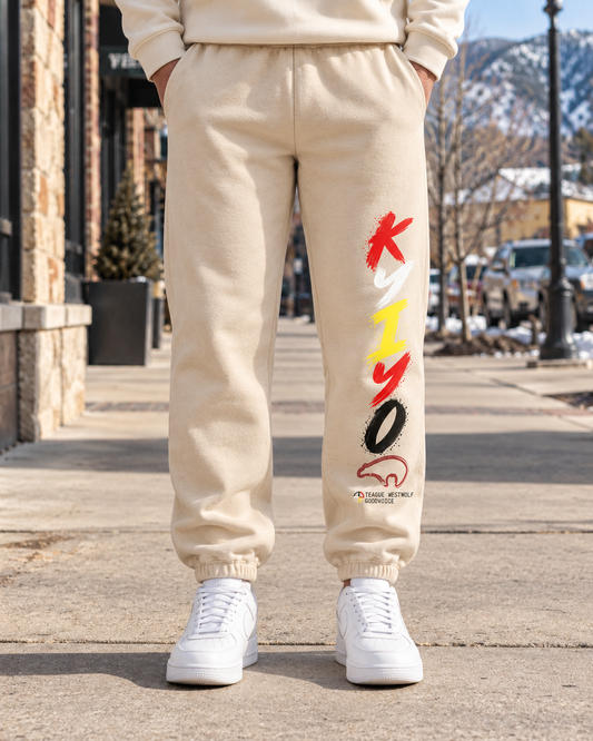 AI-generated lifestyle mockup of sand Kyiyo sweatpants with vertical KYIYO artwork on the front of the left leg.